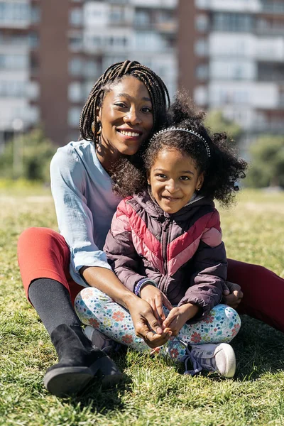 Menina Afro Bonito Sentado Grama Com Sua Mãe Sorrindo Olhando — Fotografia de Stock