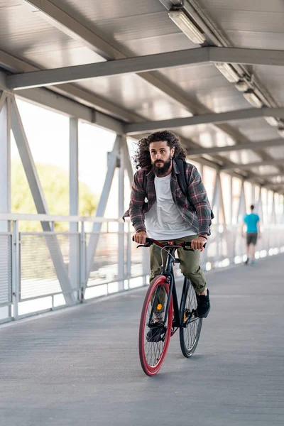 Przystojny Hipster Długimi Włosami Patrzący Przed Siebie Jeżdżący Rowerze Mieście — Zdjęcie stockowe