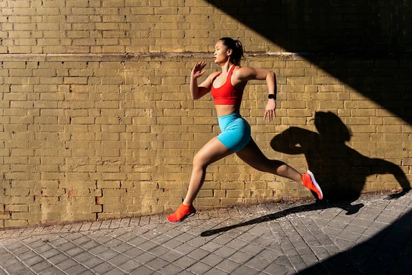 晴れた日にストリートでスポーツウェアが働いている強力なアジアの女性 彼女は走って正面を見ている — ストック写真