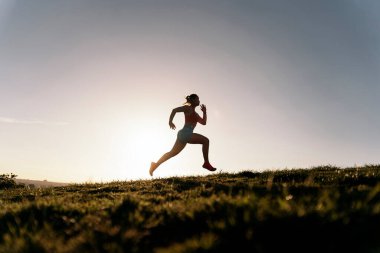 Parkta spor kıyafetleriyle koşan ve akşamları antrenman yapan tanınmamış aktif kadın..