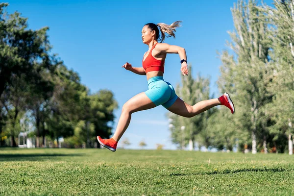 晴れた日に公園でスポーツウェアが働いている強力なアジアの女性 彼女は空を飛び跳ねている — ストック写真