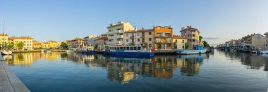Grado, İtalya - 8 Temmuz 2021: Sabah Grado 'da kanalın yuvarlak bir kısmı teknelerin sudaki yansımalarıyla