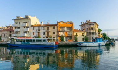 Grado, İtalya - 8 Temmuz 2021: Güzel eski renkli binalar ve demirlemiş tekneler ve balıkçı tekneleri