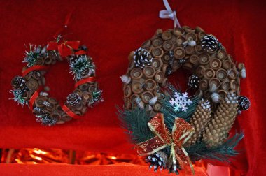 Noel konilerinden yapılmış Noel çelenkleri kırmızı bir battaniyede Noel toplarıyla süslenmiş.