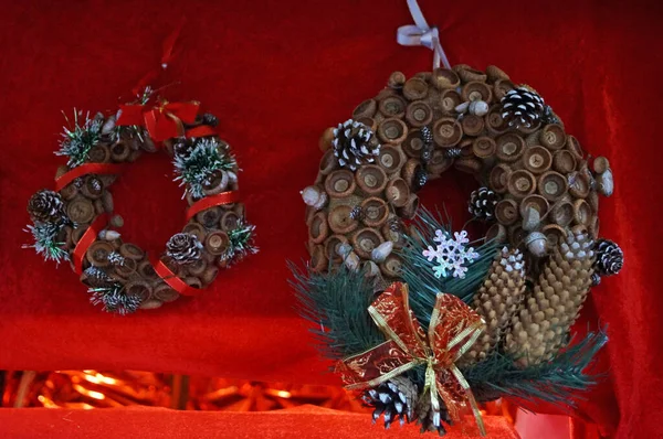 Noel konilerinden yapılmış Noel çelenkleri kırmızı bir battaniyede Noel toplarıyla süslenmiş.