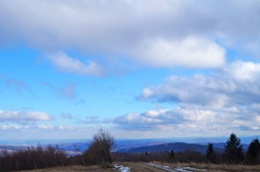 Gökyüzünün altında, bulutlu bir sonbahar gününde, beyaz ve gri bulutlarla, sonbahar Karpat dağlarının manzarası.