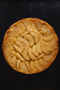 Elmalı tart, dilimlenmiş elma ve üzerine yapışkan sos. Kopyalama alanı olan koyu siyah bir arkaplan ayarla