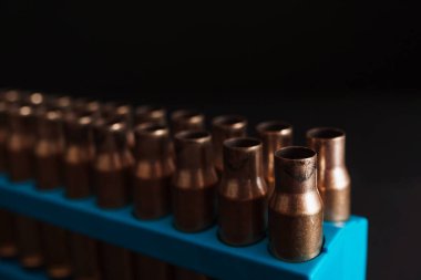 Kehribar altın boş mermi kutuları mavi tutucu içinde koyu siyah bir arkaplan ve kopyalama alanı mevcut