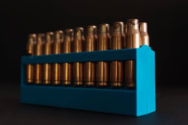 Kehribar altın boş mermi kutuları mavi tutucu içinde koyu siyah bir arkaplan ve kopyalama alanı mevcut