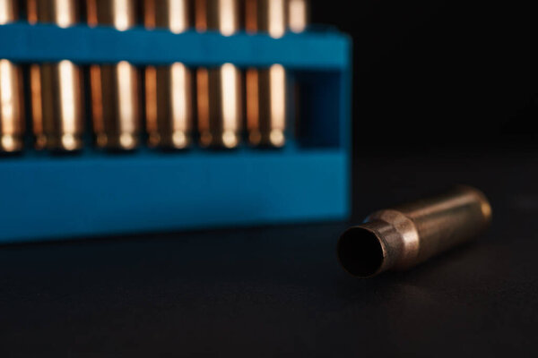 Amber gold empty bullet cases in blue holder aginst a dark black background with copy space available