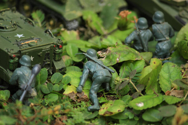Miniature infantry and tank cavalry are being stationed in the forest. Jungle battlefield camouflaged with army uniform.