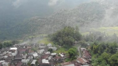 Drone video of the natural beauty of the countryside, looks at the houses of residents in the countryside, with beautiful mountain views.