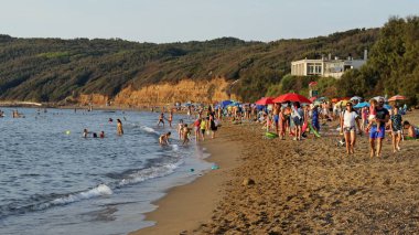 Baratti, Tuscany, İtalya - 13 Ağustos 2021: Plajda turistlerle birlikte gün batımında Baratti plajı.