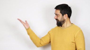 Yakışıklı sakallı bir adam elinde bir şeyle gülümsüyor, bir ürünü parmağıyla gösteriyor, hayali bir nesne sunuyor..