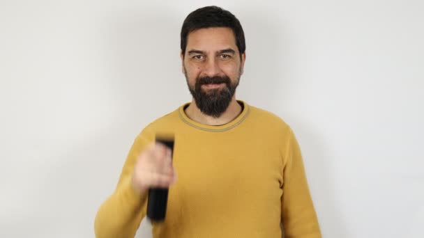 独立した白い背景に髭を生やした男がカメラを指差す手にリモコンを持っている — ストック動画