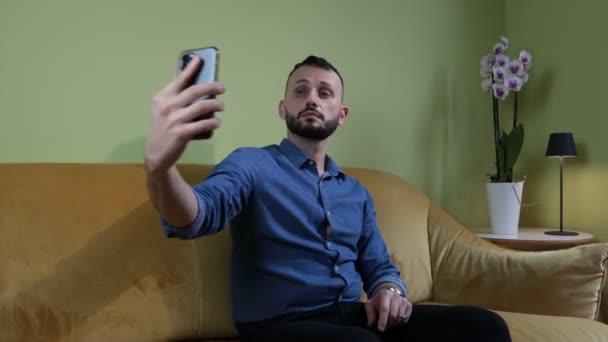 Man Duduk Sofa Rumah Membuat Selfie Dengan Smartphone — Stok Video