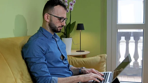 Evde dizüstü bilgisayarla çalışan sakallı bir adam. Akıllı çalışma konsepti.