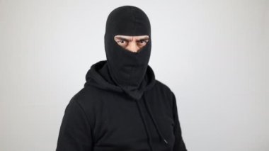 İzole edilmiş beyaz arka planda kar maskesi giyen bir adam tabanca tutuyor. Suç kavramı