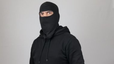 Siyah kar maskeli adam yumruk savunma hareketiyle savaşmaya hazır. Haydut ya da hırsız beyaz arka plandaki kameraya bakın. Suç kavramı