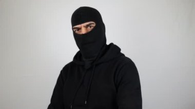 Çapraz kollu kar maskeli adam kameraya bakıyor. Suç kavramı