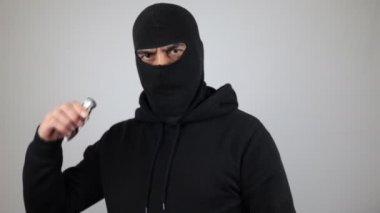 Bıçağı tutan siyah kar maskeli adam. Haydut ya da hırsız beyaz arka plandaki kameraya bakın. Suç kavramı