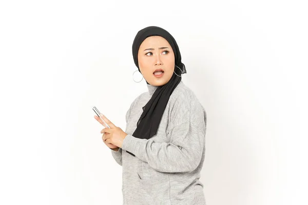 笑顔と白い背景に隔離されたヒジャブを身に着けている美しいアジアの女性のスマートフォンを使用して — ストック写真