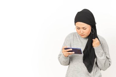 Beyaz arka planda izole edilmiş tesettürlü güzel Asyalı kadının akıllı telefonunda mobil oyun oynamak