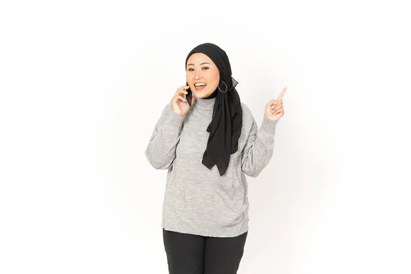 スマートフォンを使用し 白い上に孤立ヒジャブを身に着けている美しいアジアの女性の脇を指す — ストック写真