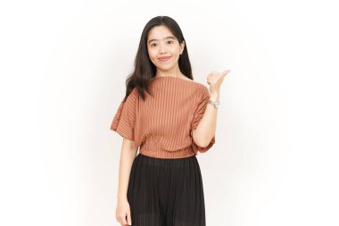 Beyaz arka planda izole edilmiş güzel Asyalı kadının başparmağını kullanarak sunar ve gösterir.