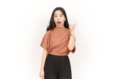 Beyaz arka planda izole edilmiş güzel Asyalı kadının başparmağını kullanarak sunar ve gösterir.