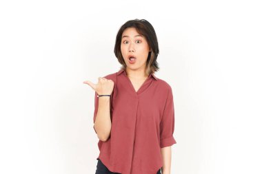 Beyaz arka planda izole edilmiş güzel bir Asyalı kadının başparmağıyla yan ürünleri gösterme ve gösterme