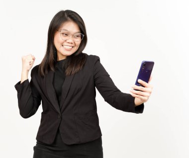 Beyaz üzerine siyah ceket giyen güzel Asyalı kadının kutlaması ve alımlı telefonu.