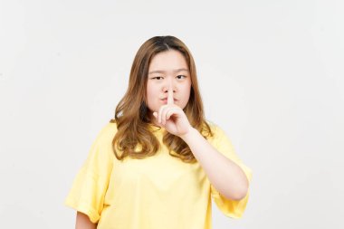 Beyaz arka planda izole edilmiş sarı tişört giyen güzel Asyalı kadının sessiz ol.