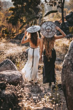 Gün batımında sahada zarif elbiseler giymiş iki güzel genç kadın.