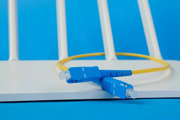 Optical fiber cable connector close-up on a router on a blue background. The concept of modern communications.