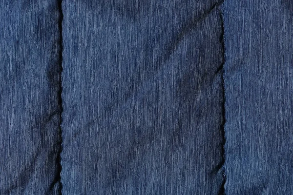 Fragment of blue fabric from a down jacket with seams. Texture, background for design.