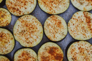Eggplant sliced in rings and sprinkled with paprika ready for baking. Top view, flat lay
