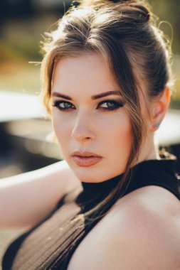 Akşam makyajı yapılmış zarif bir genç kadının portresi. Doğrudan kameraya bakıyor..