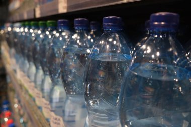 Süpermarketin rafındaki plastik şişelerde kaynak suyu. Yakın çekim seçici odak.