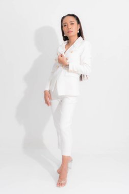 İş kadını için moda tarzı katalog kıyafetleri. Siyah uzun saç doğal makyaj. Beyaz takım elbise..