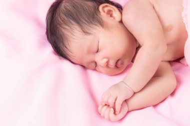 Bir aylık bir bebeğin portresi. Pembe bir battaniyenin üzerinde yeni doğmuş bir kız bebek. Yeni doğan stüdyonun konsept portresi.