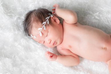 Bir aylık bir bebeğin portresi uyuyor, yeni doğmuş bir kız bebek. Taçlı bir saç bandı takıyor ve beyaz bir battaniyenin üzerinde uyuyor. Yeni doğan stüdyonun konsept portresi.