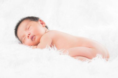 Beyaz bir battaniyenin üzerinde uyuyan, yeni doğmuş bir kızın portresi. Yeni doğan stüdyonun konsept portresi.