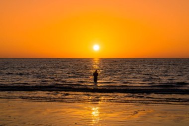 Khaolak sahilinde gün batımı yansıması ve silueti olan adam tek başına manzaraya bakıyor. turuncu gün batımı gökyüzü. Phangnga, Tayland 'da seyahat cazibesi.