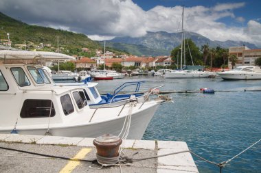 Limanda demirlemiş bir zevk yatının pruvası şehrin ve dağların arka planına karşı, Tivat, Karadağ.