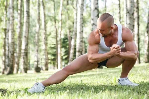 Genç atletik adam bir yaz günü huş ağaçlarının arasında spor için parka gider..