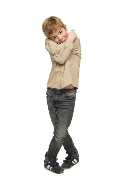 Ένα Μικρό Αγόρι Στέκεται Ένα Απομονωμένο Λευκό Φόντο Και Αγκαλιάζεται — Φωτογραφία Αρχείου