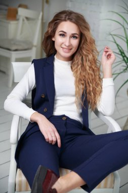 Ofisin içinde hoş bir kız günlük kıyafetlerle oturuyor..