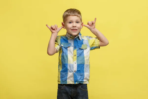 一个穿着鲜艳衬衫的可爱小男孩用双手捂住耳朵 用一种黄色的背景隔开的滑稽动作 — 图库照片