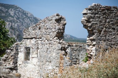 Bir yaz günü eski bir taş binayla dağ manzarası.